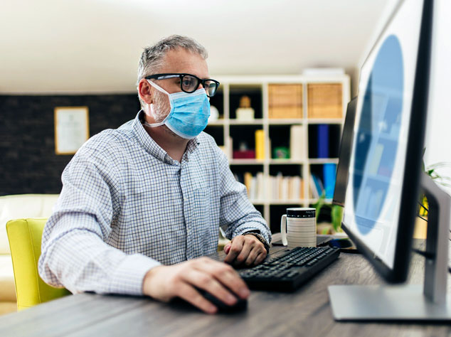 Man with mask working on computer
