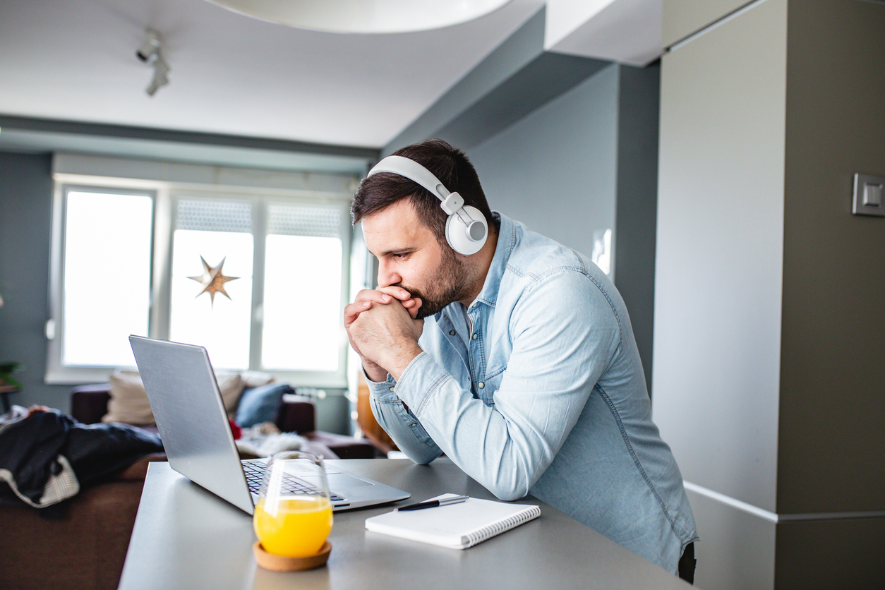 Man with headphones listening to webinar on laptop